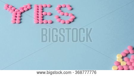 Word Yes Is Made Up Of Pink Pills On A Blue Background