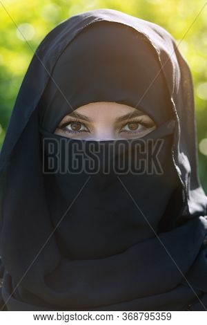 Portrait Of A Muslim Woman In Black Clothes. Islamic Woman In National Dress Close-up. Black Clothes