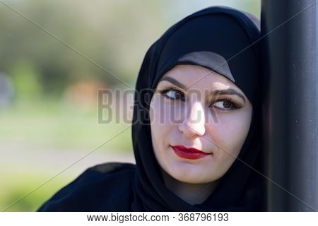 Sad Woman In Muslim Clothes. Islamic Girl In Black Clothes Sad Alone On The Street.
