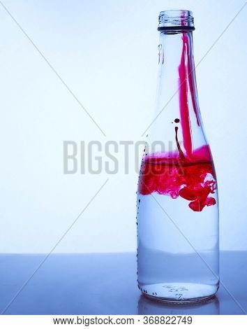 Red Ink Mixed With Water In A Glass Bottle On A Light Background