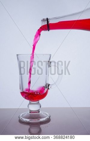 Red Liquid Poured Into A Glass Glass On A White Background With Bubbles