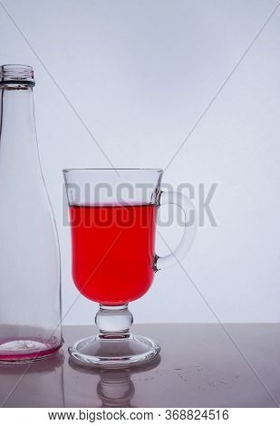 Red Liquid Into A Glass On A White Background Light Effect