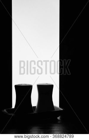 Black White Silhouettes Of Peppercorns And Salt Shakes On A White Background