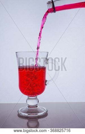 Red Liquid Poured Into A Glass Glass On A White Background With Bubbles