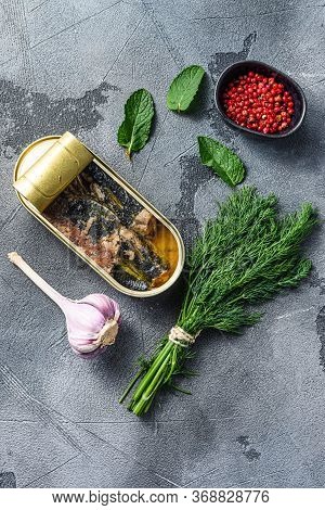 Sardinops In Oil In Preserve Canned Food, Open Can Jar Woth Herbs And Garlic Ocer Grey Background To