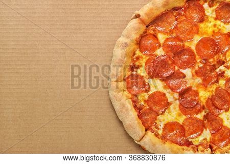 Pepperoni Pizza With Sausages, Tomato Sauce And Cheese On Brown Corrugated Fiberboard Background.