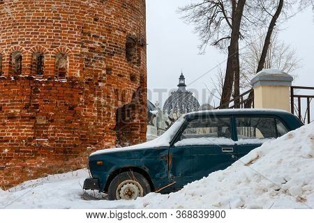 An Old Passenger Car Stands In A Snowdrift Near The Old Fortress Tower