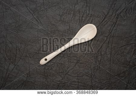 White Glazed Porcelain Coffee Spoon On Artificial Leather Background.