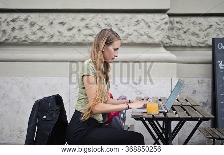 
beautiful teener works with computers in an outside bar