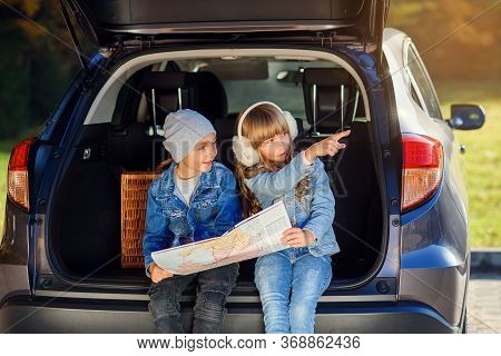 Agreeable Boy And Girl Are Looking At The Road Map While Sitting In The Autos Trunk And Discussing T
