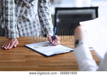 Girl Standing Looks At Report Lying On Table Men. Reorganization Period And Quarantine Uncertainty. 