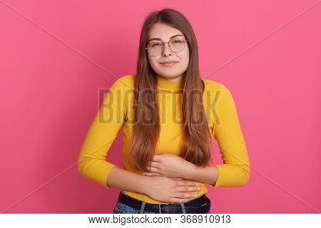 Young Female Wearing Casual Yellow Shirt And Eyewear Touching Her Stomach, Suffering From Abdominal 