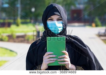 An Islamic Woman In National Women's Clothing Holds A Holy Book With Prayers In Her Hands Muslim Wom