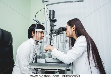 Consultation With An Ophthalmologist. Young Asian Man And Woman Doctor