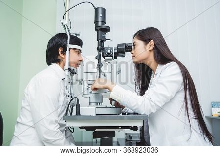 Consultation With An Ophthalmologist. Young Asian Man And Woman Doctor