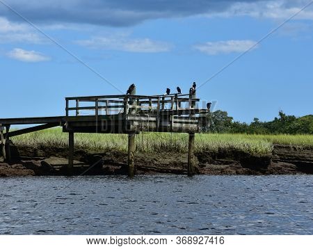 Dark Gray Clouds Over A Pier And A Marsh.