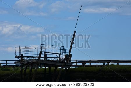 Long Fishing Pier Over A Tidal Marsh And River.