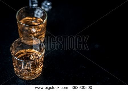 Whisky, Whiskey, Bourbon Or Cognac With Ice Cudes On Black Stone Table