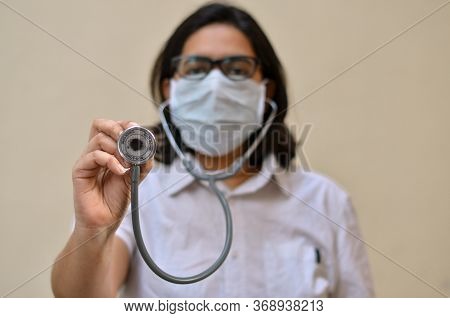 Portrait Of Young Medical Healthcare Female Worker Showing / Holding Out Her Stethoscope & Wearing S