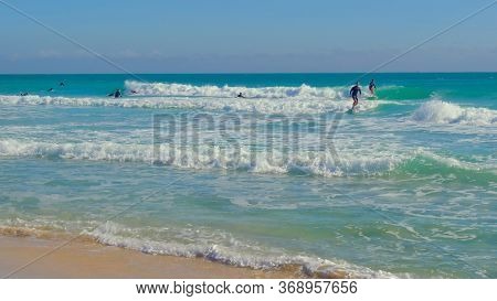 Surfers Catch The Wave. Surfers Ride Small Waves Performing The Initial Exercises While Learning To 