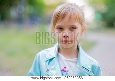 Close Up Portrait Of Young 6-7 Year Old Girl. Girl 7 Years Old Outdoors Portrait In A Blue Jacket. L