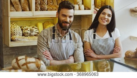Portrait Of The Attractive Male And Female Young Co-workers, Bakers Standing At The Counter In The S