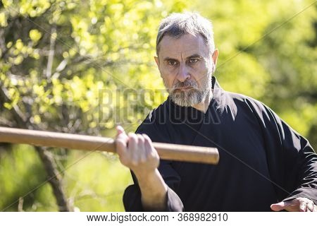 Adult Kung Fu Master Practicing Wushu With A Stick In The Park