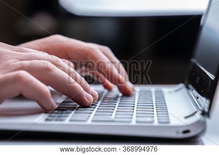 Close-up Of Mens Hands Typing On Laptop Keyboard At The Desk. Unrecognizable Man Is Writing Email On