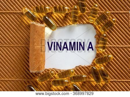 The Text 'vitamin A' Appearing Behind Torn Brown Paper. Yellow Pills.