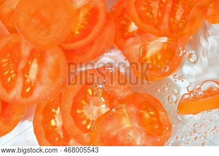 Close-up View Of The Red Tomato Slices In Water Background. Texture Of Cooling Vegeteble Drink With 
