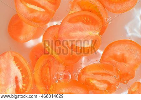 Close-up View Of The Red Tomato Slices In Water Background. Texture Of Cooling Vegeteble Drink With 