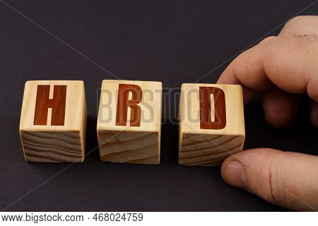 Business Concept. On A Black Surface, A Man Puts Cubes With The Inscription - Hrd