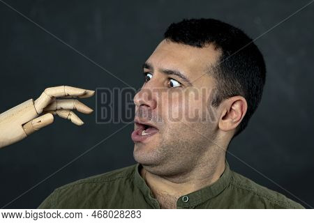 Portrait Of A Frightened Man 30-35 Years Old, Looks With Horror At A Wooden Model Of An Attacking Ha