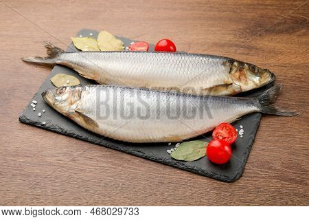Slate Plate With Salted Herrings, Bay Leaves And Cherry Tomatoes On Wooden Table