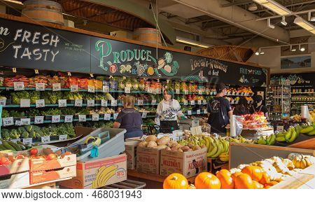 People Shopping In The Supermarket. Buyer Shopping Groceries In Supermarket. Woman Employee Restocki