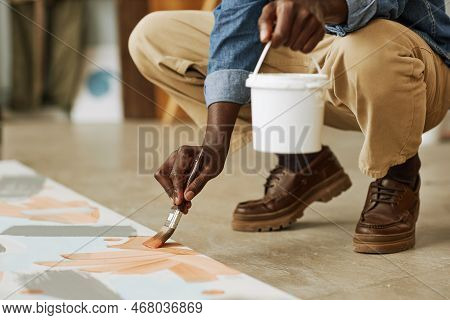 Low Section Of African American Male Artist Painting Artwork On Canvas While Squatting On Rhe Floor 