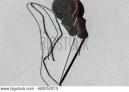 Sewing Needle Threader Tool In Use And A Single Black String.