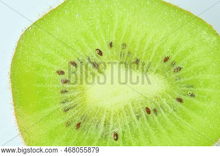 Close-op Of Kiwi Fruit With Bubbles. Bright View Photo. Kiwi Fruit Slice In Water With Bubbles On Li