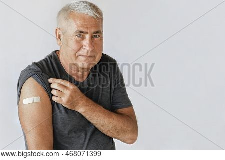 Male Senior Smiling After Receiving Vaccine. Old Man Showing Arm With Bandage, Patch After Vaccine F