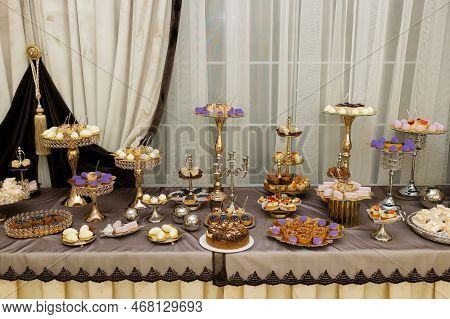 Table With Cakes, Sweets, Candy, Buffet. Dessert Table For A Party Goodies For The Wedding Banquet A