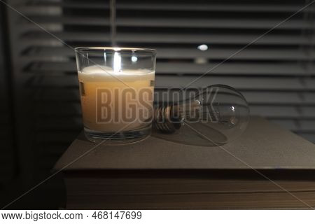The Light Bulb Lies In A Dark Empty Room By The Window By The Light Of A Candle (close-up). Blackout