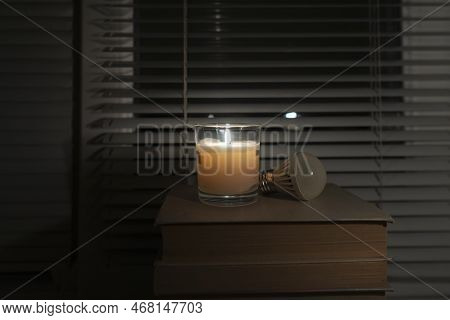 An Led Light Bulb Lies In A Dark Empty Room By The Window By The Light Of A Candle (close-up). Black