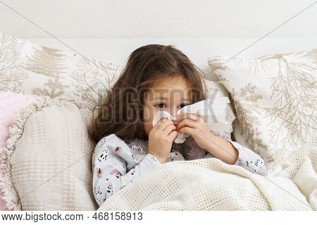 Little Girl Blow Stuffy Nose With White Handkerchief. Portrait Of Unhealthy Child. Kid In Sleepwear 