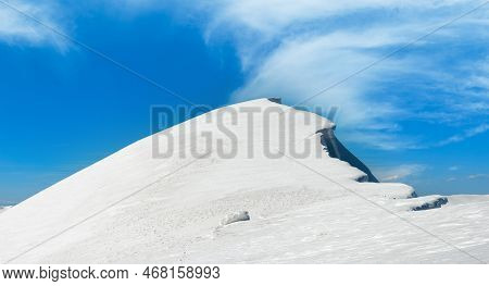 Winter Mountains Ridge With Overhang Snow Caps And Snowboard Tracks On Blue Sky Background (ukraine,