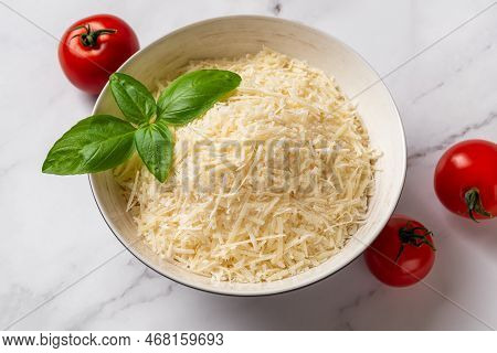 Bowl Of Shredded Parmesan Over Marble Background. Grated Grana Padano Cheese And Red Tomatoes Prepar