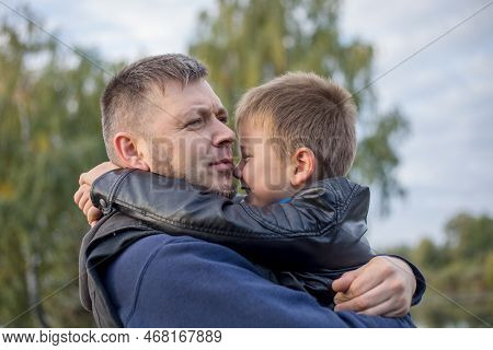 Happy Father And Son Hugging And Playing Together In Green Nature. Fisherman's House With A Wooden P
