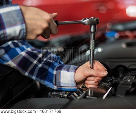 Female Auto Mechanic Unscrewing A Nut To Replace A Car Spark Plug.