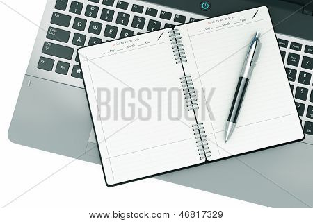 Bloc-notes et un stylo sur un clavier d'ordinateur portable