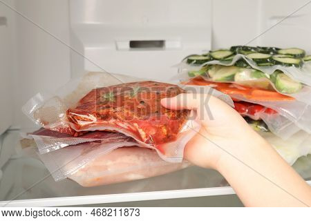 Woman Putting Vacuum Packs With Meat Into Fridge, Closeup. Food Storage
