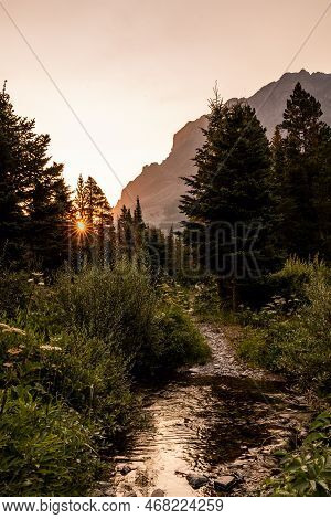 Sunburst Glows Orange Over Cut Bank Creek In Glacier National Park
